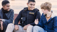 male police officer in uniform talking to kids