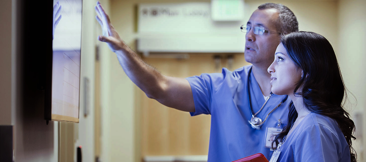 Nurse looking at a whiteboard with a colleague