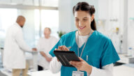 Young smiling nurse in scrubs working on a computer tablet