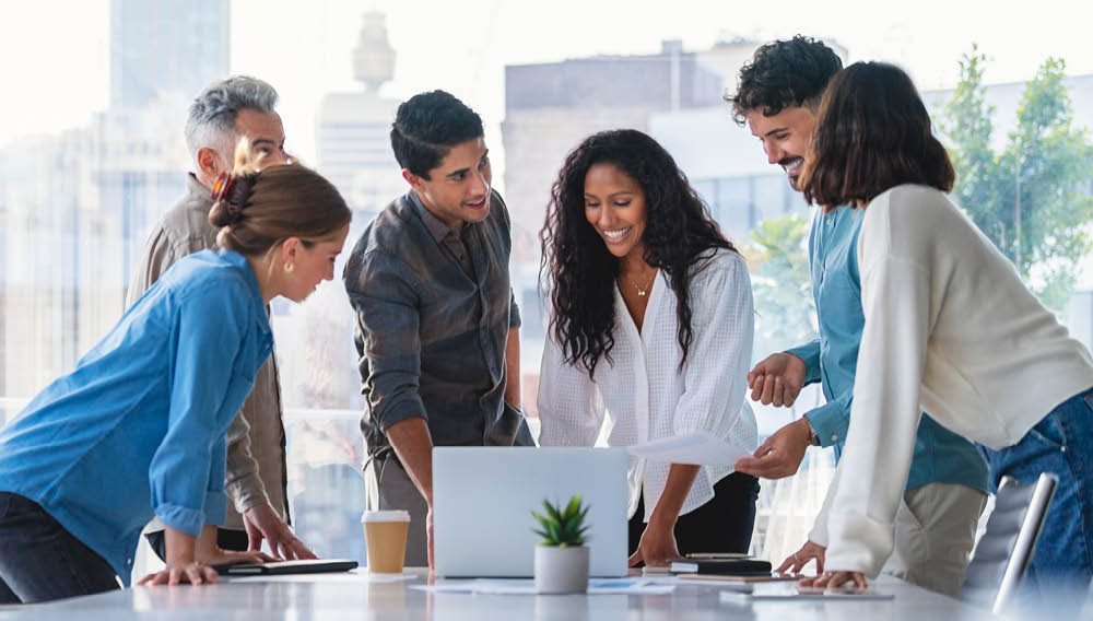 Engaged employees standing around a table with a laptop on it