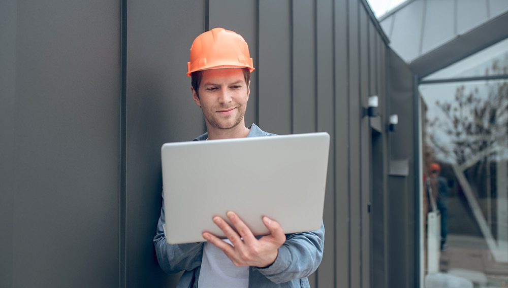 Electrical engineer holding a laptop on a construction site