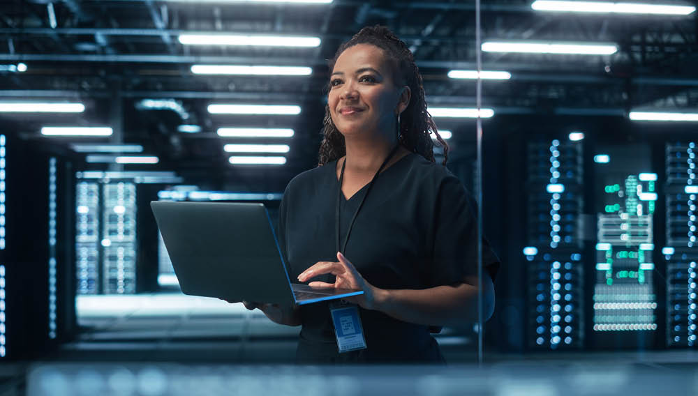 Network architect standing with a laptop in a computer server room