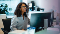 Smiling receptionist sitting at a desktop computer