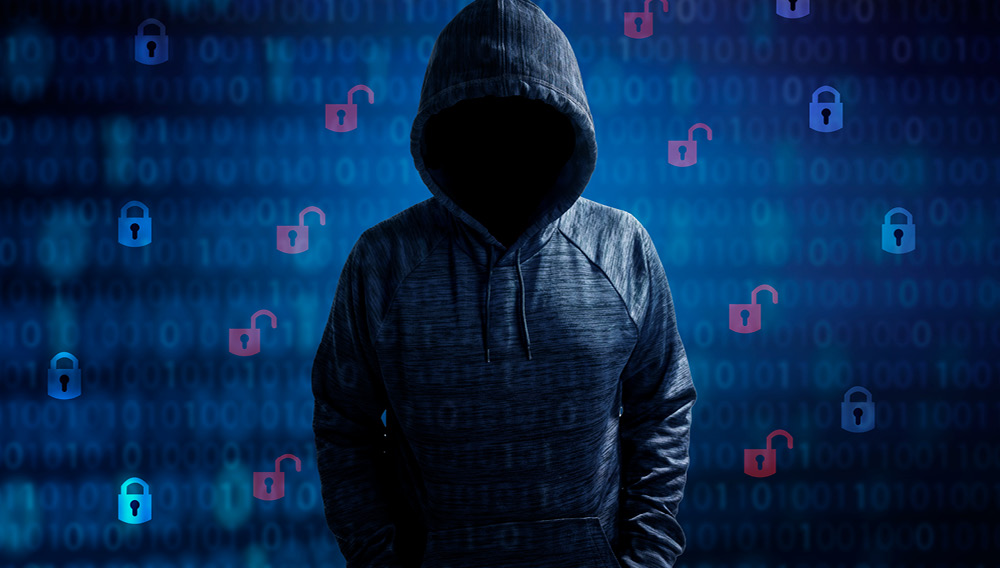 Threat actor obscured by a hoodie in front of a backdrop of binary code and open padlocks