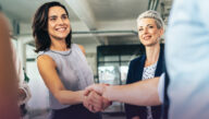 A smiling businesswoman shakes hands at a networking event.